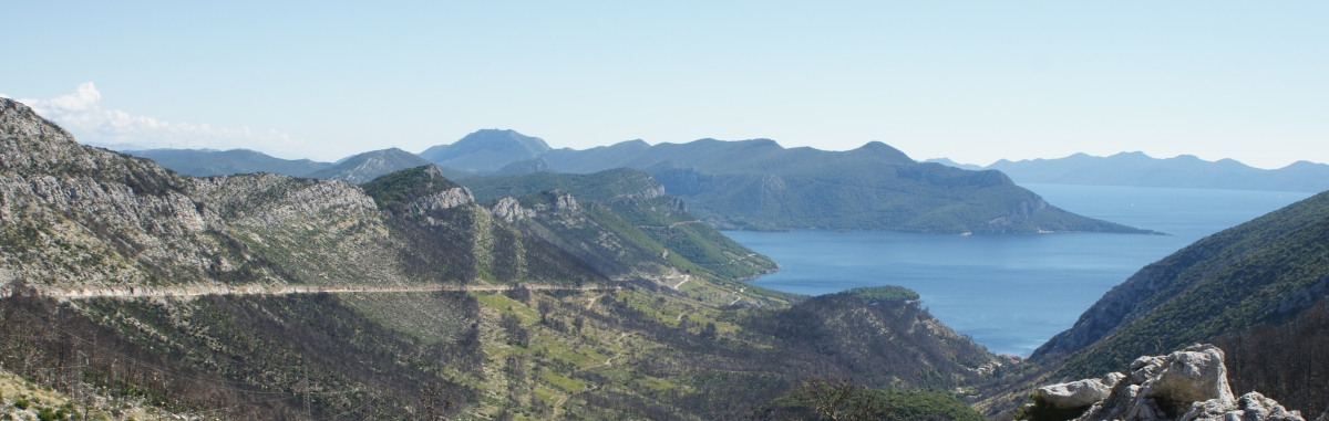 A picture of a Croatian landscape showing mountains, serpentine roads, and the sea.