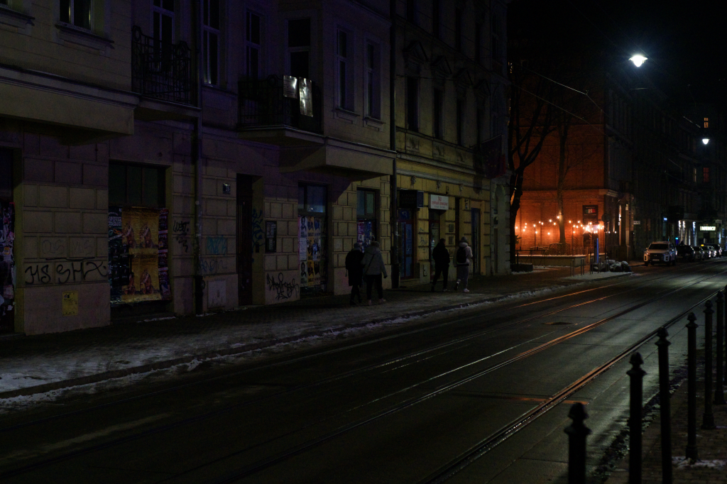 Young people walking along a street at night.